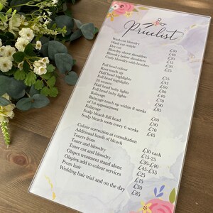 May include: A price list for hair salon services. The list includes prices for wash and blow dry, root touch up, highlights, weaves, balayage, color correction, toners, olaplex treatments, prom hair, and wedding hair.