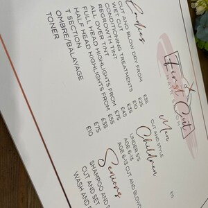 May include: A white price list for a hair salon called "First Cut" with prices for various services, including cuts, blow dries, conditioning treatments, tints, and highlights. The prices are listed in British pounds.