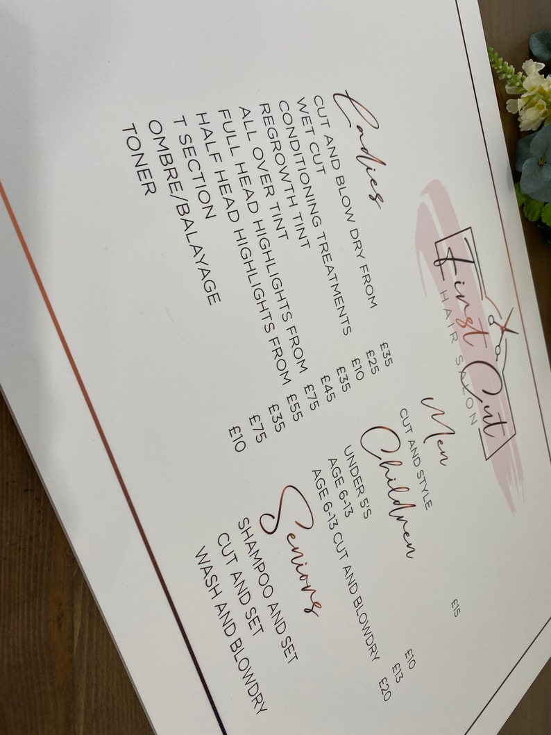 May include: A white price list for a hair salon called "First Cut" with prices for various services, including cuts, blow dries, conditioning treatments, tints, and highlights. The prices are listed in British pounds.