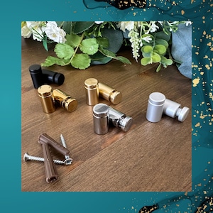 May include: Assortment of metal picture hanging hardware in gold, silver, and black. The hardware includes hooks, screws, and anchors.