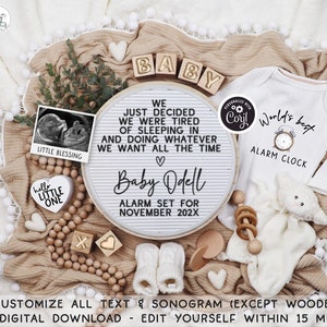 以下が含まれることがあります： 「We just decided we were tired of sleeping in and doing whatever we want all the time」と「Baby Odell Alarm Set for November 202X」と書かれた白いレターボード。レターボードは、木製のブロック、ベビーロンパース、木製ガラガラ、小さな超音波画像で囲まれています。