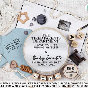 Peut inclure: Un tableau d'affichage blanc avec le texte "The Tired Parents Department I Love You, It's Ruining My Sleep Baby Swift I'm Having His Baby March 202X". Le tableau d'affichage est entouré d'une variété d'articles sur le thème des bébés, notamment une grenouillère bleue avec le texte "Wild Boy Wild Joy", une étoile en bois, un hochet en bois, un cercle en bois avec le texte "Boys Are Swifties Too" et une petite machine à écrire en bois.