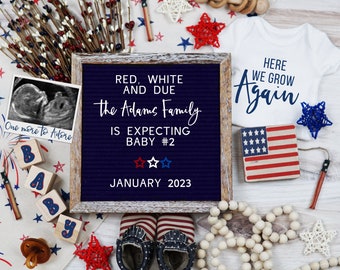 May include: A letter board with the text "RED, WHITE AND DUE The Adams Family IS EXPECTING BABY #2 JANUARY 2023".  The board is surrounded by red, white, and blue baby items, including a onesie, booties, a rattle, and a wooden block set.