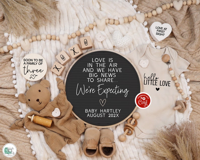 K&ouml;nnte beinhalten: Ein schwarzes Buchstabenbrett mit dem Text "Love is in the air and we have big news to share... We're Expecting" mit einem Herz und dem Text "Baby Hartley August 202X". Es gibt Holzbl&ouml;cke, die "XOXO" buchstabieren, und ein Holzschild, auf dem "Soon to be a family of three" mit einem Herz steht. Es gibt einen Teddyb&auml;r, einen Baby-Strampler mit dem Text "hello little love" und einem Herz und eine Holzrassel.