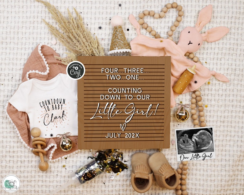 May include: A brown wooden sign with white text that reads "Four...Three...Two...One...Counting Down To Our Little Girl!" with a heart and the date "July 202X". The sign is surrounded by baby items including a white onesie with the text "Countdown To Baby Clark", a pink bunny rattle, a wooden rattle, a gold party hat, a pink and white blanket, a gold and black party popper, a pair of brown baby booties, and a black and white ultrasound image with the text "Our Little Girl".