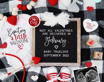 Könnte beinhalten: Ein weißer Strampler mit dem Text "Expecting a little Valentine" und einem roten Herz. Eine Buchstabentafel mit dem Text "Not all Valentines are delivered in February... Baby Truelove September 2022". Eine rot-weiß karierte Decke mit roten Filzherzen, ein Paar rote Babyschuhe und ein Ultraschallbild.
