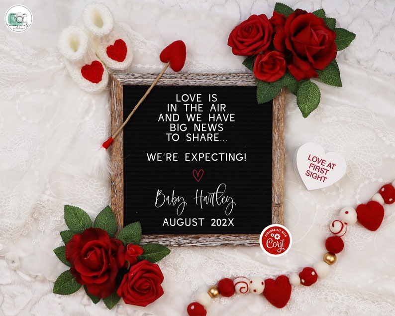 May include: A black letter board with the text "Love is in the air and we have big news to share... We're expecting! Baby Harley August 202X". The board is surrounded by red roses, white hearts, and a white string of beads with red and white hearts.
