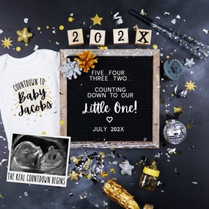 May include: A black letter board with the text "FIVE...FOUR...THREE...TWO...COUNTING DOWN TO OUR Little One! JULY 202X" surrounded by gold and silver confetti, a baby onesie with the text "COUNTDOWN TO Baby Jacobs", a black and white ultrasound image, a gold bottle of champagne, a baby bottle, a silver disco ball, and wooden blocks spelling out "202X".