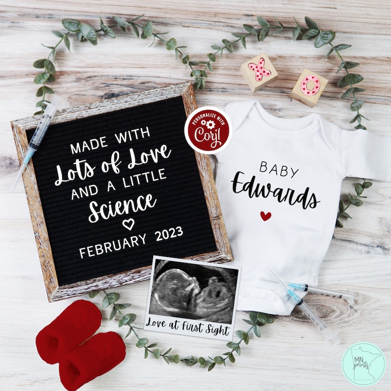 May include: A white onesie with the text "BABY Edwards" and a red heart. A letter board with the text "MADE WITH Lots of Love AND A LITTLE Science FEBRUARY 2023". A black and white ultrasound image with the text "Love at first Sight".