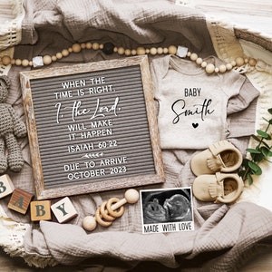 May include: A brown wicker basket filled with baby items, including a letter board with the quote "When the time is right, the Lord will make it happen. Isaiah 60:22" and the text "Due to arrive October 2023", a white onesie with the text "Baby Smith", a pair of brown moccasins, a wooden rattle, a teddy bear, and a framed ultrasound image with the text "Made with Love".