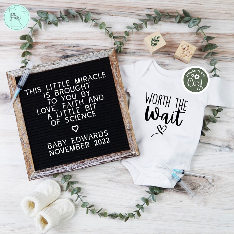 May include: A white onesie with the text "WORTH THE WAIT" and a heart. A black letter board with the text "THIS LITTLE MIRACLE IS BROUGHT TO YOU BY LOVE, FAITH AND A LITTLE BIT OF SCIENCE. BABY EDWARDS NOVEMBER 2022".