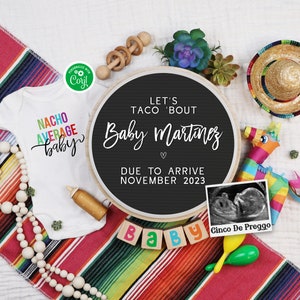 May include: A black chalkboard sign with the text "Let's Taco 'Bout Baby Martinez" and "Due to Arrive November 2023". The sign is surrounded by a variety of Mexican-themed baby shower decorations, including a white onesie with the text "Nacho Average Baby", a wooden rattle, a small wooden bottle, a string of wooden beads, a small succulent plant, a colorful pinata, a maraca, a sombrero, and a framed ultrasound image with the text "Cinco De Preggo".