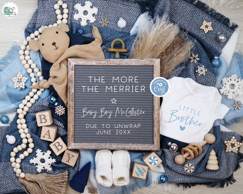 May include: A blue and white blanket with a letter board that reads "The More The Merrier Baby Boy McCallster Due To Unwrap June 20XX". There is a white onesie with the text "Little Brother" and a brown teddy bear with a blue and white blanket.