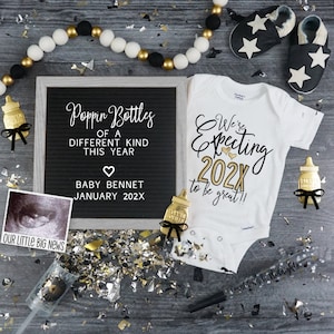 May include: A black letter board with the text "Poppin Bottles of a Different Kind This Year" and "Baby Bennet January 202X". A white onesie with the text "We're Expecting 202X to be great!!" and a black and white ultrasound image.