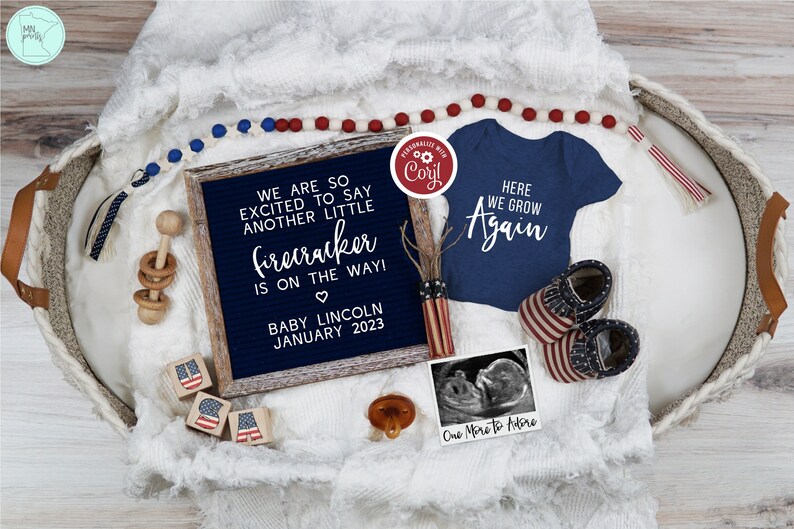 May include: A white letter board with the text "We are so excited to say another little firecracker is on the way! Baby Lincoln January 2023". A red, white, and blue baby onesie with the text "Here we grow again". A red, white, and blue baby rattle, a red, white, and blue pacifier, and a red, white, and blue baby shoe.
