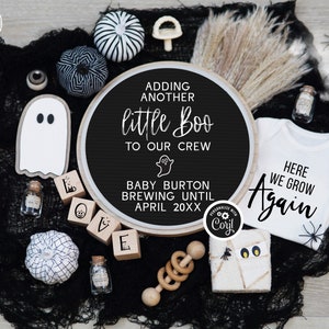 May include: A black and white Halloween-themed baby announcement with a round sign that reads "Adding another little Boo to our crew. Baby Burton brewing until April 20XX". There are also black and white pumpkins, a ghost, and a baby onesie that reads "Here we grow again".