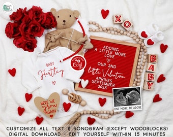 May include: A red and white baby onesie with the text "Baby Hartley" and a red heart. A red letter board with the text "Adding a little more love. Our 2nd little Valentine arrives September 202X". A teddy bear holding a bow and arrow. Red felt hearts, wooden blocks that spell "BABY", and a wooden bead garland.