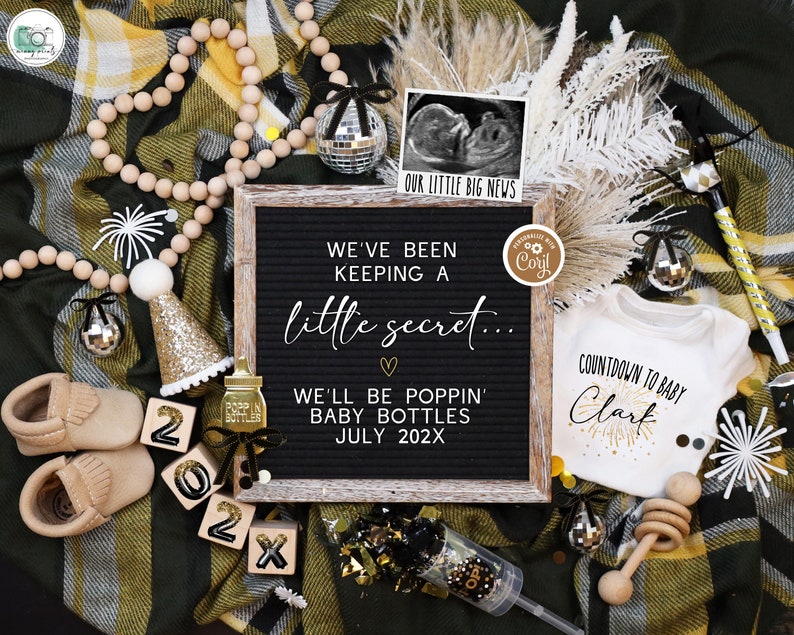 May include: A black letter board with the text "We've been keeping a little secret... We'll be poppin' baby bottles July 202X". A white onesie with the text "Countdown to baby Clark" and a gold glitter firework design. A wooden bead garland, a gold glitter party hat, a baby bottle with a gold glitter bow, and a wooden rattle.