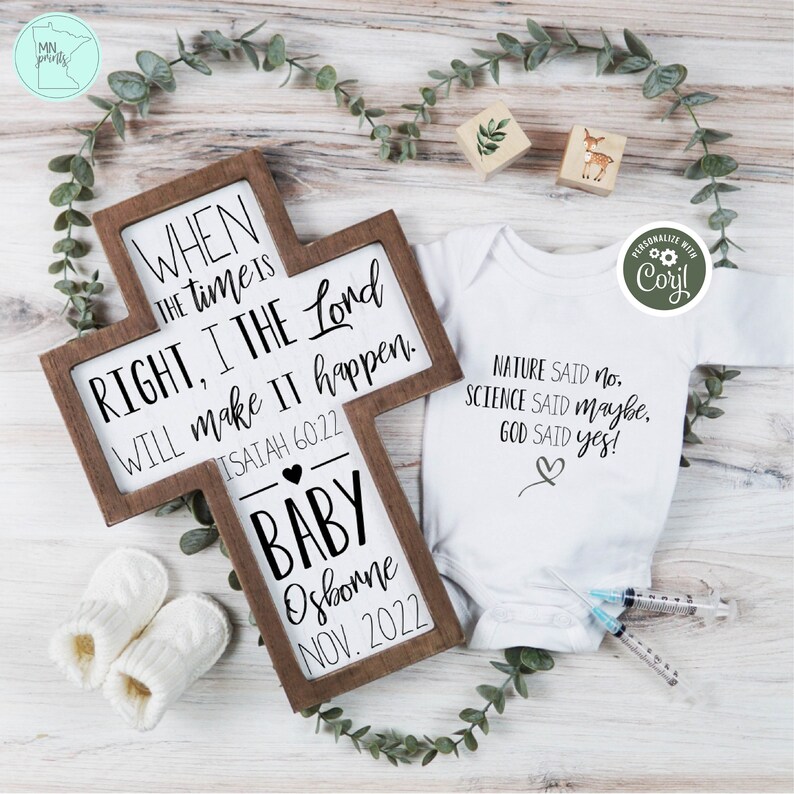 May include: A wooden cross with the text "WHEN THE TIME IS RIGHT, I THE LORD WILL MAKE IT HAPPEN. ISAIAH 60:22" and "BABY Osborne NOV. 2022". A white onesie with the text "NATURE SAID no. SCIENCE SAID maybe, GOD SAID yes!"