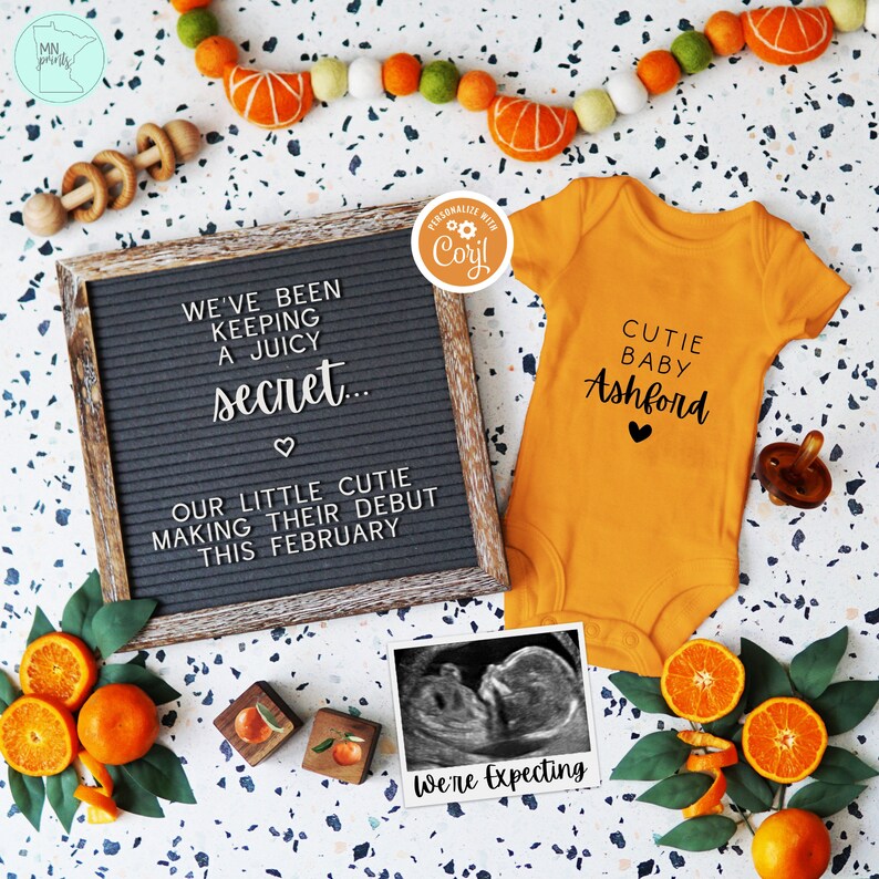 Op de afbeelding: Een zwart letterbord met de tekst "We've been keeping a juicy secret... Our little cutie making their debut this February."  Een gele romper met de tekst "Cutie Baby Ashford" en een hartje. Een echografiebeeld met de tekst "We're expecting".