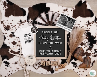 May include: A rustic baby announcement with a chalkboard sign that reads "Saddle Up! Baby Dutton is on the way! Due to arrive February 2024". The sign is surrounded by a variety of baby items, including a onesie, a pair of baby boots, a wooden rattle, and a wooden bead garland.