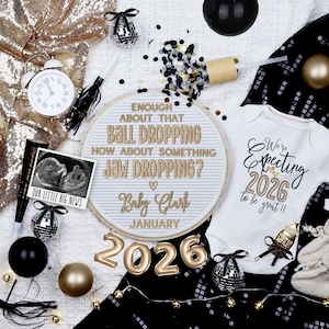 May include: A festive announcement of a baby's arrival. The image features a white onesie with "We're Expecting 2026" text, a letter board, sonogram, and gold "2026" balloons. Black and gold confetti and decorations complete the celebratory theme.