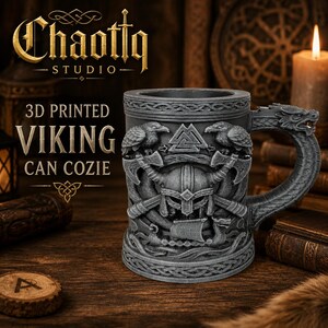 May include: A gray 3D printed can cozie featuring a relief design of a Viking helmet, two ravens, crossed axes, a longship, and a Valknut symbol. The handle is shaped like a dragon head. Text on the image reads Chaottq STUDIO 3D PRINTED VIKING CAN COZIE.