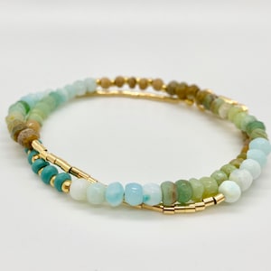 May include: A double-wrap bracelet with gold beads and green, blue, and white gemstone beads.