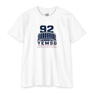 May include: A white short-sleeve t-shirt featuring a dark blue graphic of a stadium with the number 92 above it. Below the stadium, the text reads YEMSG, NEW YORK CITY, and the dates JULY 22, 24, 25, 27, 29, 2026 in blue and red ink.