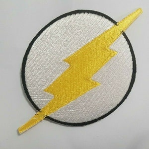 May include: A white and yellow embroidered patch with a lightning bolt design. The patch is circular and has a black outline.