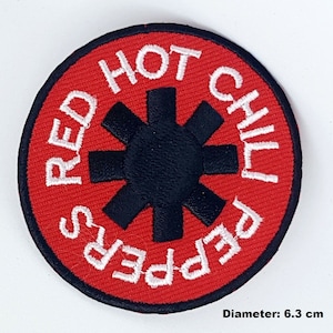 May include: Red Hot Chili Peppers embroidered patch with a black starburst logo on a red background. The text "Red Hot Chili Peppers" is white and circles the starburst. The patch is 6.3 cm in diameter.
