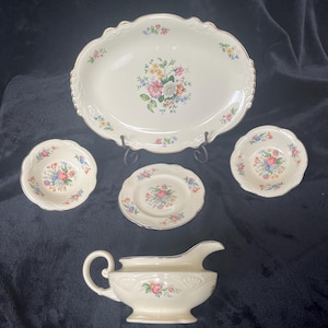 May include: A set of vintage white porcelain dishes with a floral pattern. The set includes a large oval serving platter, two small bowls, a small plate, and a gravy boat.