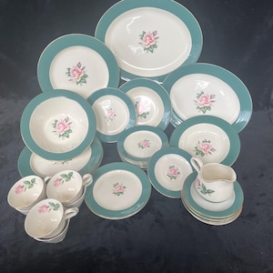 Puede incluir: Un juego de vajilla de porcelana vintage con un patrón floral verde y blanco. El juego incluye platos, tazones, tazas y platillos.