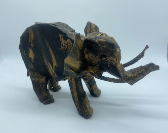 May include: A black and gold metal elephant sculpture with a textured finish. The elephant is standing on all four legs with its trunk raised.