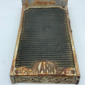 May include: A vintage metal washboard with a black rubber surface and the word "KARN" embossed in the bottom. The washboard has a decorative design around the edges.