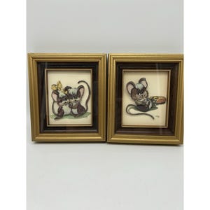 May include: Two framed vintage prints depicting charming cartoon mice. One print shows two mice with a butterfly, the other shows a mouse with a snack. The frames have a gold border and a dark brown inner frame.