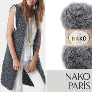 Può includere: Un gomitolo di filato grigio e soffice con il marchio "NAKO PARIS" sull'etichetta. Il filato è adatto per la maglia o l'uncinetto.