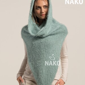 May include: A light blue hooded scarf with a fuzzy texture. The scarf is knitted and has a triangular shape. The brand name "NAKO" is visible on the scarf.