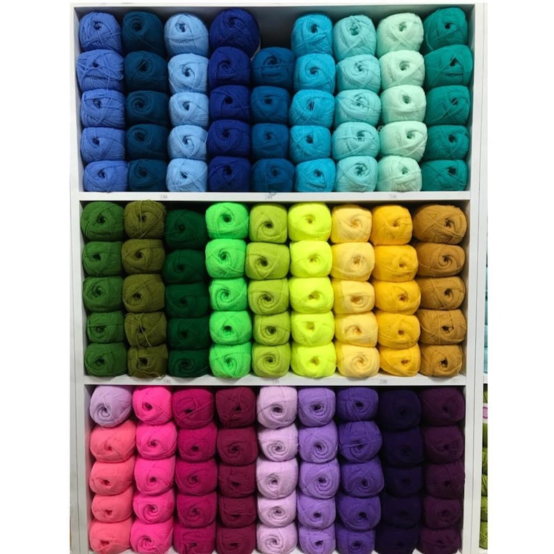 May include: A shelf filled with colorful yarn balls in various shades of blue, green, yellow, pink, and purple.
