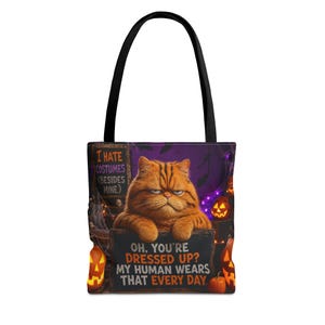 Puede incluir: Un bolso tote negro con un gráfico de un gato atigrado naranja con expresión gruñona. El texto dice: I HATE COSTUMES (BESIDES MINE) y OH, YOU'RE DRESSED UP? MY HUMAN WEARS THAT EVERY DAY. El fondo incluye calabazas de Halloween iluminadas.