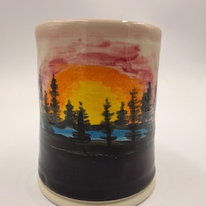 Puede incluir: Una taza de cerámica blanca con un asa negra y el texto "But First, Coffee" en un estilo manuscrito. La taza está sobre una superficie blanca. La taza mide aproximadamente 10 cm de alto.