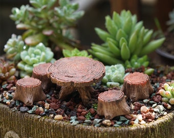 May include: A miniature wooden table and chairs set, ideal for a fairy garden or dollhouse. The set is made of brown wood and has a rustic, natural look. The table is round and has a slightly raised edge. The chairs are small and have a simple design.