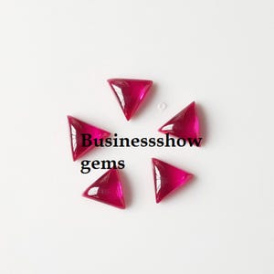 Puede incluir: Seis gemas triangulares de color rojo rubí dispuestas en círculo. Las gemas son translúcidas y tienen una superficie pulida. El texto "Businesssshow gems" está impreso en negro.