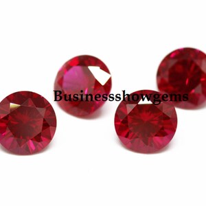 Puede incluir: Cuatro piedras preciosas redondas, facetadas y de color rojo intenso dispuestas en grupo. Cada piedra presenta un corte brillante con múltiples superficies reflectantes. El texto Businessshowgems está superpuesto en negro en el centro.