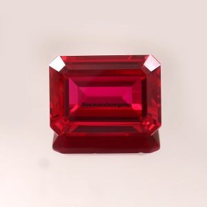 May include: A deep red emerald cut gemstone with a polished finish. The gemstone is set against a white background. The text "BusinessShowgems" is visible in the center of the gemstone.