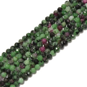May include: A strand of green, pink, and black gemstone beads. The beads are faceted and round, and they are strung on a clear thread.