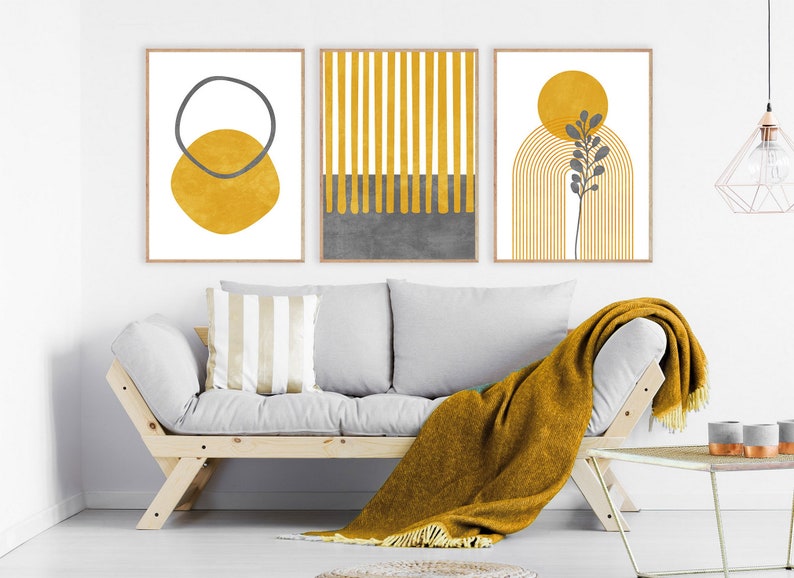 May include: Three abstract art prints in a minimalist style with a yellow and gray color scheme. The prints feature geometric shapes, lines, and a stylized plant.