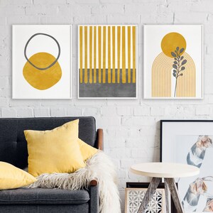 May include: Three minimalist abstract art prints with a yellow and gray color scheme. The prints feature geometric shapes, lines, and a stylized plant.