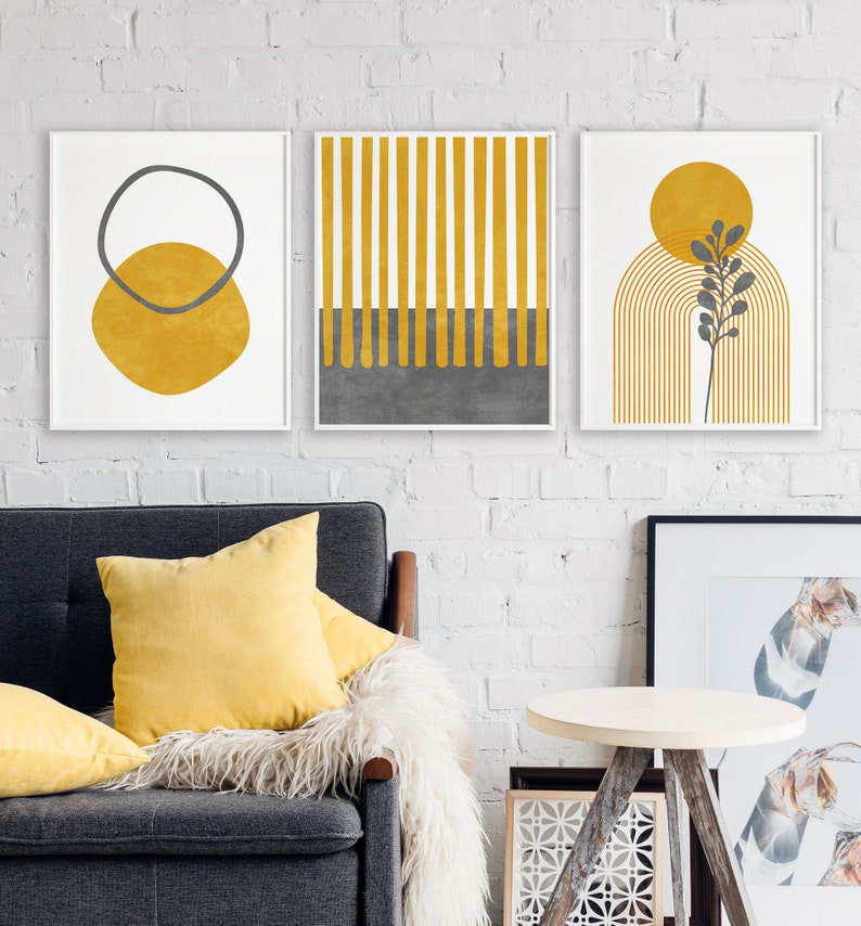 May include: Three minimalist abstract art prints with a yellow and gray color scheme. The prints feature geometric shapes, lines, and a stylized plant.