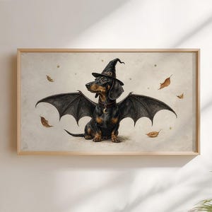 May include: A framed horizontal wall art print featuring a black and tan dachshund wearing a pointed witch hat and large bat wings. The dog has a collar with a crescent moon charm. The background is a light cream colour with floating autumn leaves.